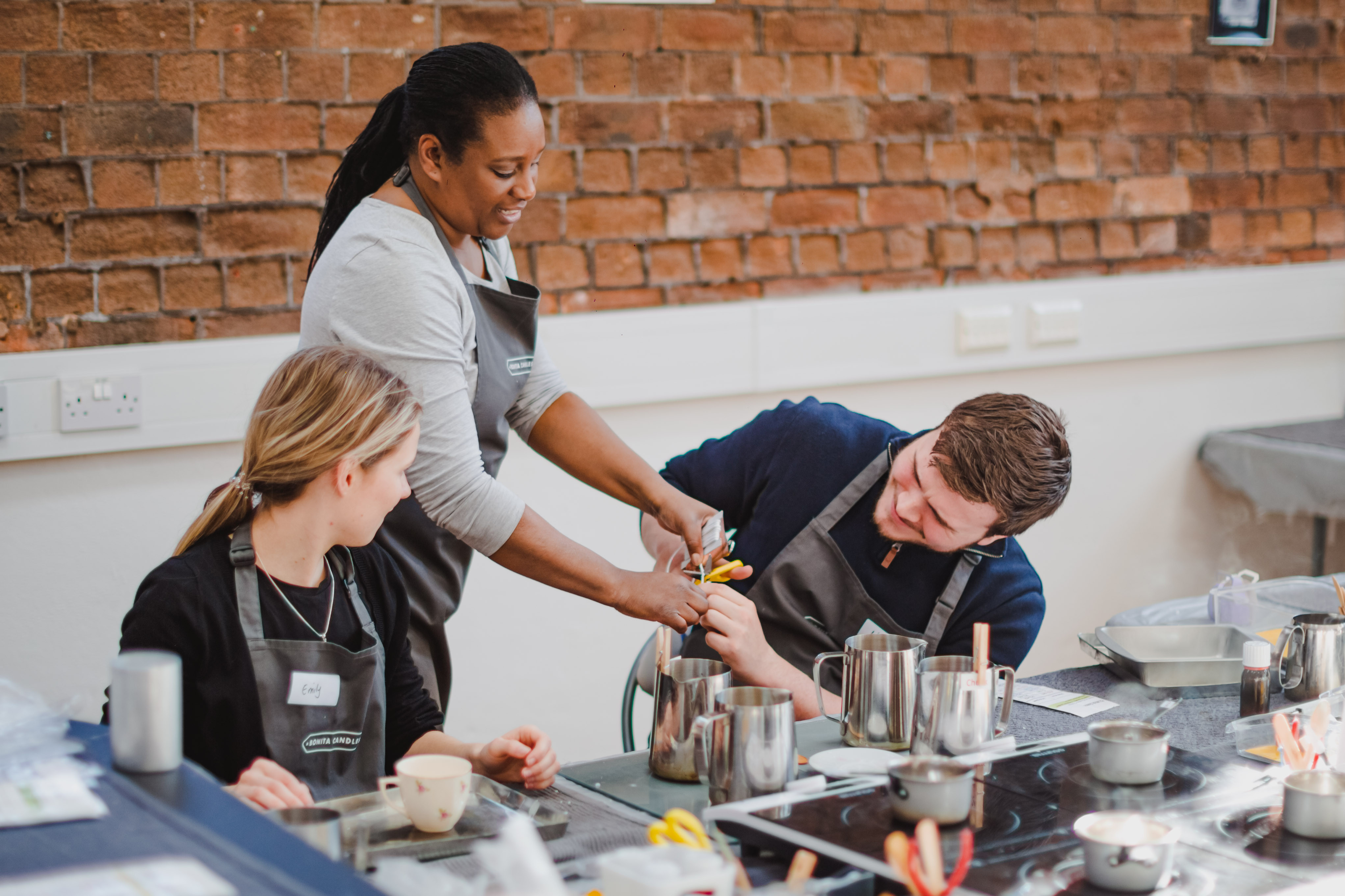 A couple learning from their teacher how to make candles